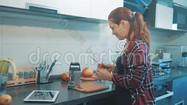 那个女孩把胡萝卜揉在数字平板<strong>电</strong>脑上的<strong>烤盘</strong>上。 美丽的女人在烹饪和测试食物